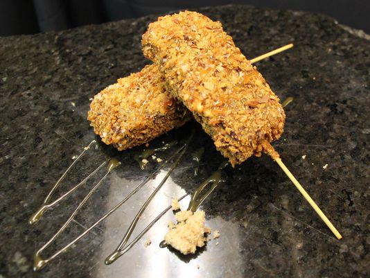 Pretzel crusted deep-fried brownie on a stick with caramel drizzle